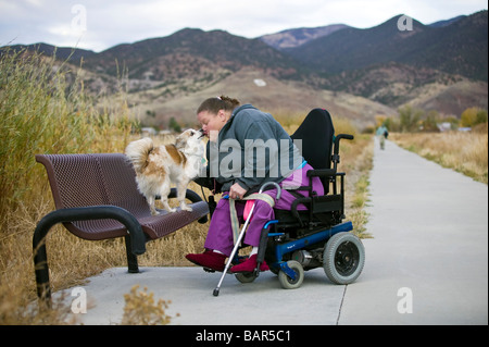 Woman uses her electric wheelchair to navigate the walking path in the small mountain town of Salida Colorado USA Stock Photo