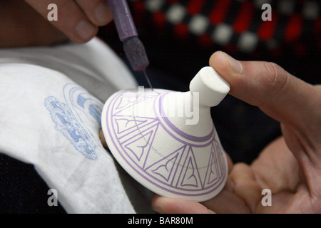 Craftsman hand paints unglazed pottery at a ceramics factory  in the medina/old town, Fes el-bali, Fes, Morocco, North Africa Stock Photo