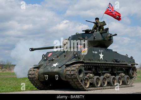 A fully restored IV Sherman tank flying the World War Two Canadian flag. Its main gun has just been fired. Stock Photo