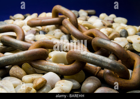 Rusted chain lying on pebbles Stock Photo