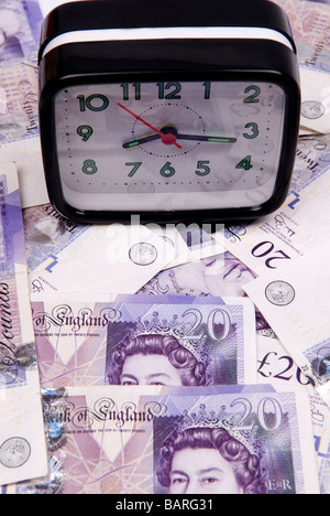 Alarm clock over a pile of British money Stock Photo