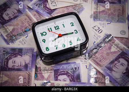 Alarm clock over a pile of British money Stock Photo