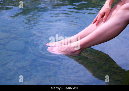 Young woman soaking feet in river low section Stock Photo