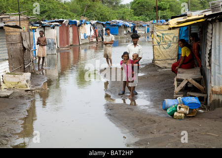 Villagers in their Hazira slum street, with receding flood water. Hazira, Surat, Gujarat. India. Stock Photo