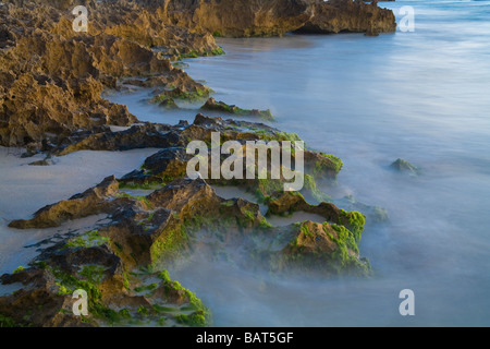 Time lapse exposure used on waves around coastal rocks to produce moody misty effect Stock Photo