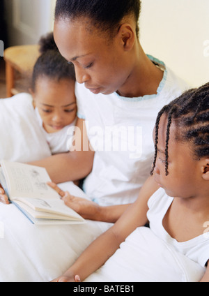 Bedtime reading. Motherreading a book to her four-year-old daughter (atleft) and five-year-old son at bedtime. Stock Photo