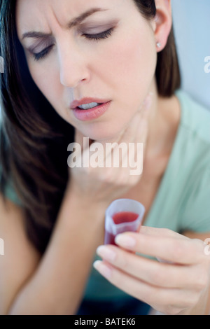 Cough medicine. Woman taking a measured dose of cough medicine. Stock Photo