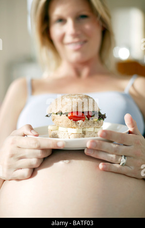 Pregnant woman eating a sandwich. Stock Photo