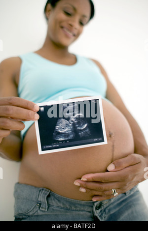 Pregnant woman holding anultrasound scan of her unborn child. Stock Photo