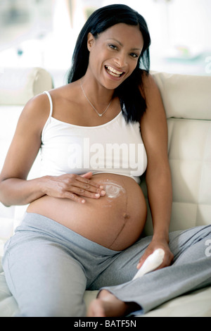 Pregnant woman applying cream to her stretch marks. She is in full terms Stock Photo