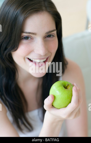 Woman holding an apple. She is inher twenties. Stock Photo