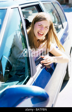 Road rage. Young woman shoutingout of a car window. Stock Photo