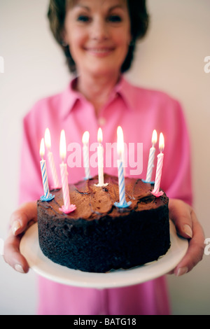 Birthday cake. Woman carrying a birthday cake with lit candles. Stock Photo