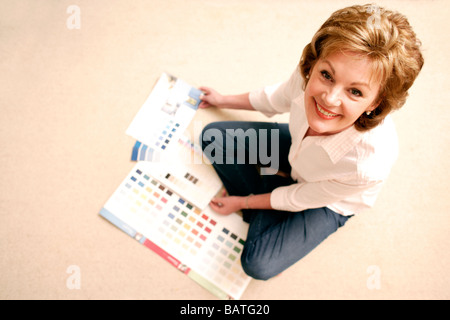 Home improvement. Woman looking through paint colour charts. Stock Photo