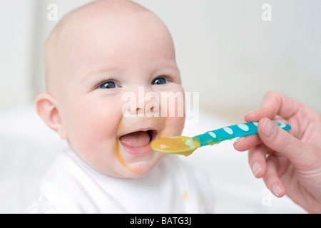 Spoon-feeding. 7 month old baby girl being spoon-fed. Stock Photo