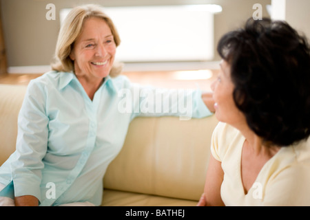 Friendship. Two female friends chatting on a sofa at home. Stock Photo