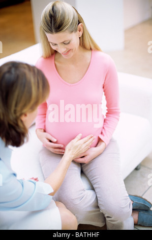 Obstetric examination. Midwife touching a pregnant woman's abdomen. Stock Photo