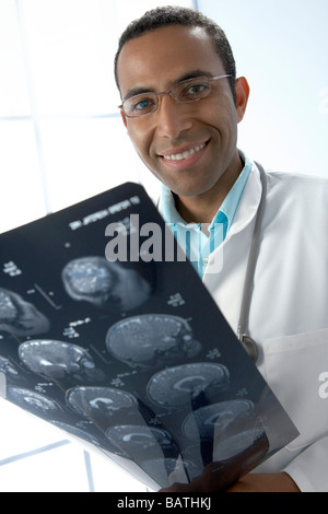 Doctor holding MRI scans. The scans are sagittal (vertical and sideways) sections through a patient head. Stock Photo