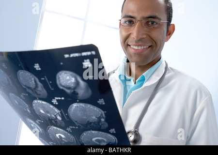 Doctor holding MRI scans. The scans are sagittal (vertical and sideways) sections through a patient head. Stock Photo