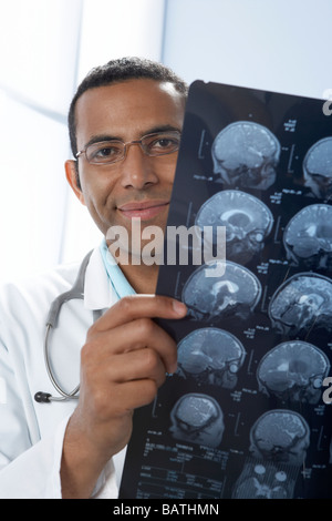 Doctor holding MRI scans. The scans are sagittal (vertical and sideways) sections through a patient head. Stock Photo