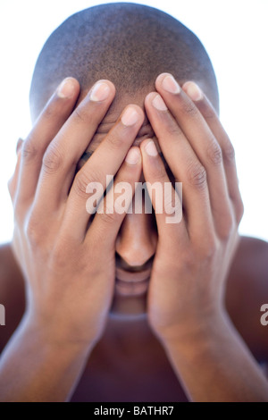 Depressed man holding his face in his hands. He is twenty years old. Stock Photo