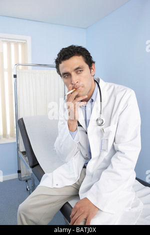 Doctor smoking a cigarette. Cigarettes contain the addictive drug nicotine and cancer causing substances Stock Photo