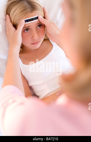 Ill child. Mother checking her daughter's temperature with a stripthermometer. Stock Photo