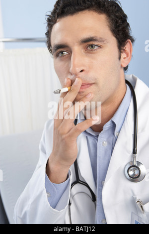 Doctor smoking a cigarette. Cigarettes contain the addictive drug nicotine and cancer causing substances Stock Photo