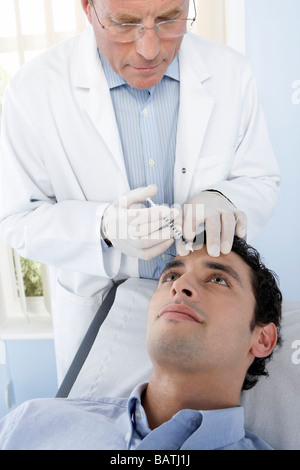 Botox treatment. Patient having botox injected into his face. Botox is a neurotoxin used for cosmetic purposes. Stock Photo