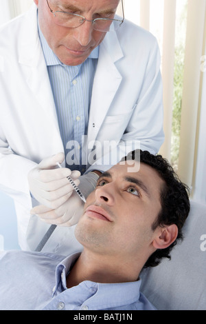 Botox treatment. Patient having botox injected into his face. Botox is a neurotoxin used for cosmetic purposes. Stock Photo