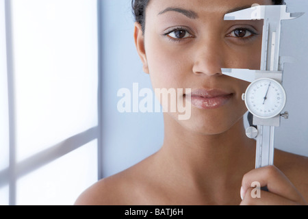 Cosmetic surgery, conceptual image. Young woman holding a pair of measuring calipers. Stock Photo