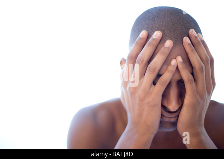 Depressed man holding his face in his hands. He is twenty years old. Stock Photo