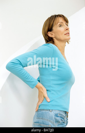 Lower back pain. Woman holding her painful lower back. Stock Photo