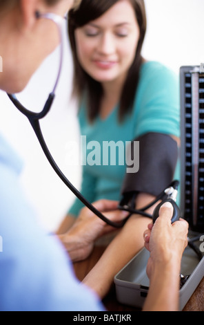 Blood pressure measurement. General practice doctor using asphygmomanometer and stethoscope to measure blood pressure. Stock Photo