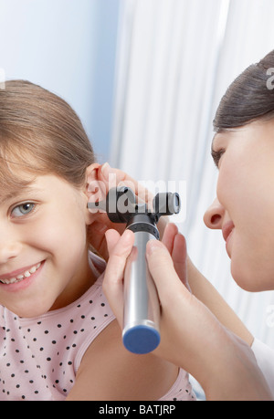 Ear examination. Otoscope being used by a general practice doctor to examine a six-year-old girl's ear. Stock Photo