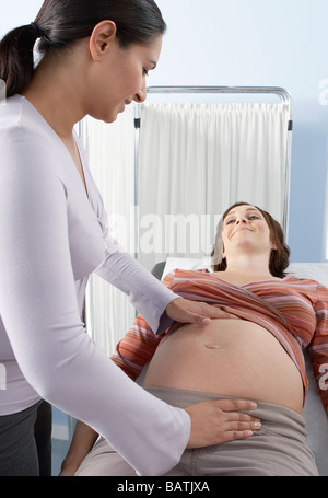 Obstetric examination. Doctor pressing a pregnant woman's abdomen. Stock Photo