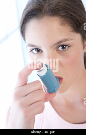Using asthma inhaler. Girl using her inhaler to treat an asthma attack. Stock Photo