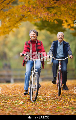 African couple riding bicycles in park in autumn Stock Photo