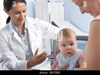 Vaccination. 5-month-old baby girl having a vaccine injected into her arm from a syringe. Stock Photo
