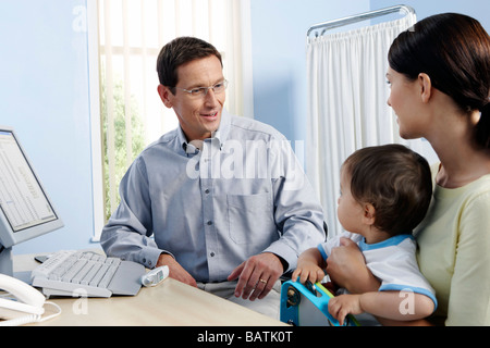 Paediatric examination. Mother and her one year old son visiting their family doctor. Stock Photo