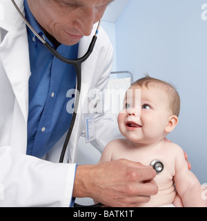 Paediatric examination. Doctor uses a stethoscope to listen to the chest (heartand lung sounds) of a five month old baby girl. Stock Photo