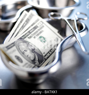 Medical costs. Conceptual image of US dollar bills in a surgical kidney dish. Stock Photo