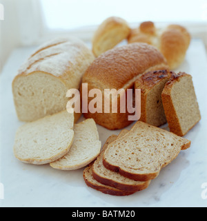 Assorted breads. Three loaves of bread with rolls of bread in the background. Stock Photo