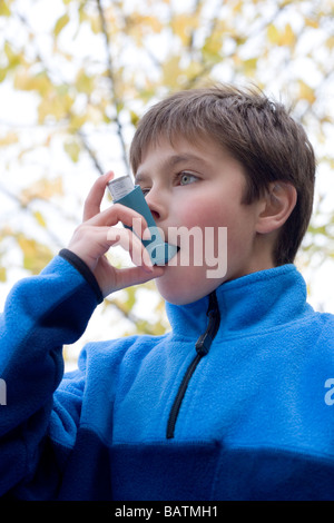 Treating an asthma attack. Boy using an inhaler to treat an asthma attack. Stock Photo