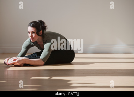 Woman performing stretching exercise, studio shot Stock Photo