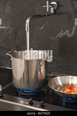 Water pouring from tap into pot Stock Photo