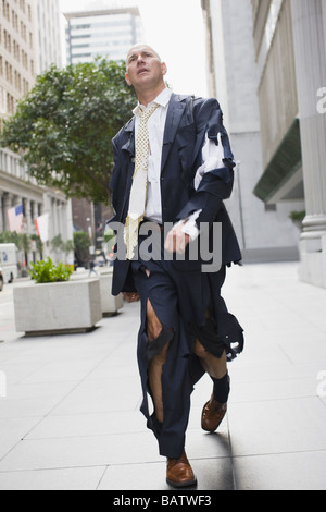 USA, California, San Francisco, Businessman wearing torn clothing, walking in street Stock Photo