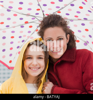 Mother and daughter (10-11 years) under umbrella, portrait