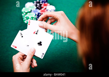 young woman playing poker holding three aces in hand Stock Photo