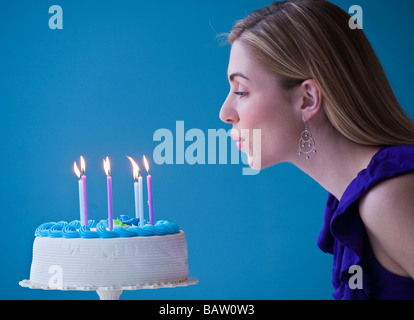 Young woman blowing candles on birthday cake, studio shot Stock Photo